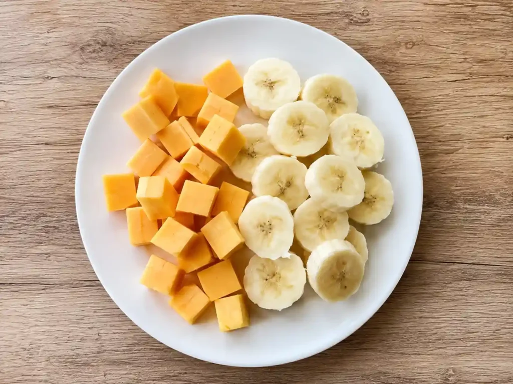 Finger Foods for 1 Year Old: 50+ Safe, Easy & Nutritious Ideas 5 small cheese cubes and banana pieces in white ceramic plate